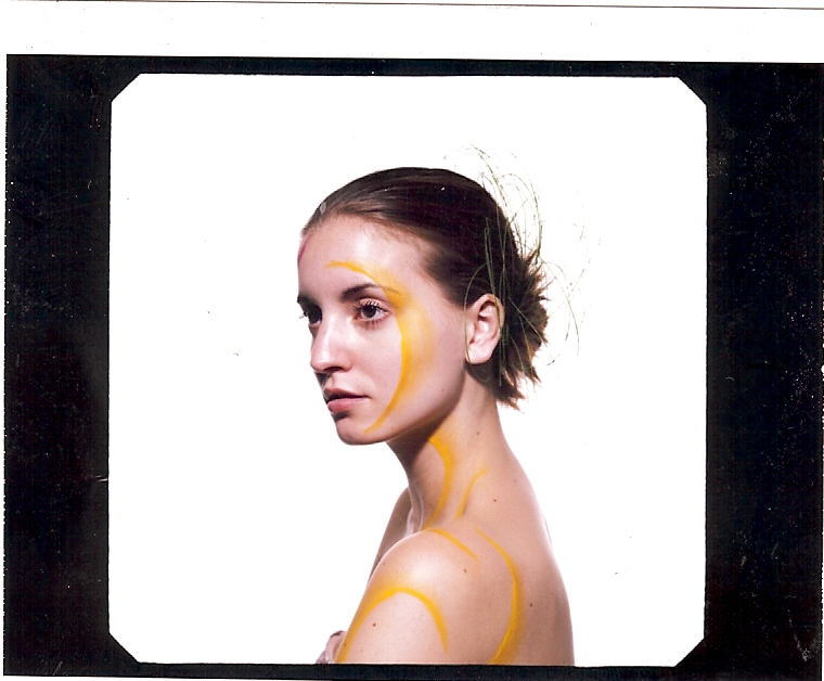 Portrait with flowing golden body paint against a bright backdrop
